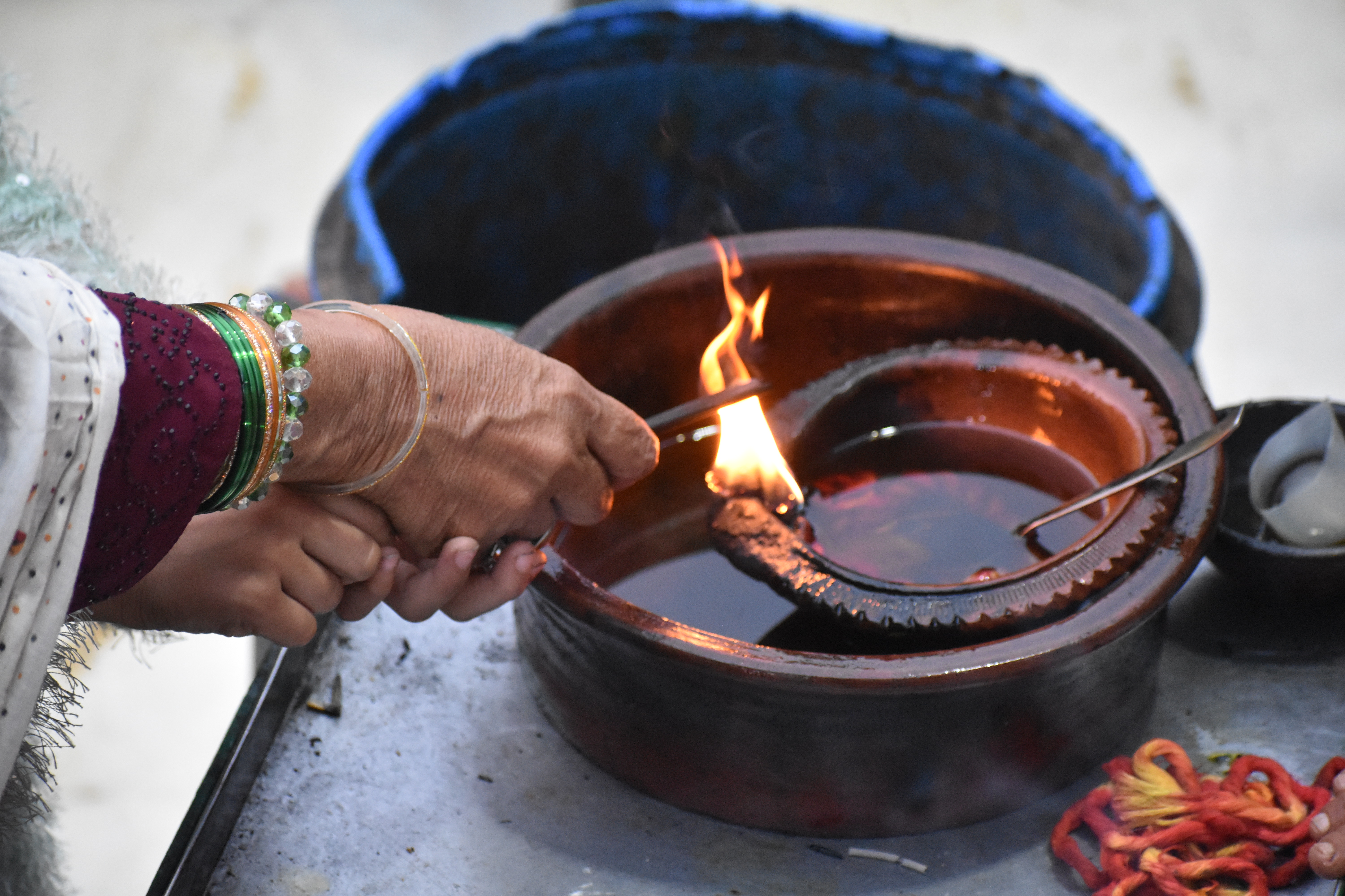 A woman lights up an incense stick from a dia (earthen lamp) to offer at the dargah