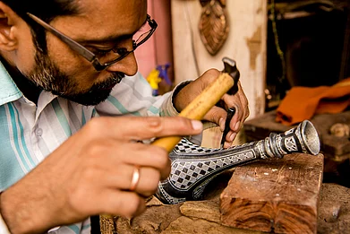 Akella Srinivas Ramalingaswami/Shutterstock : A Bidri craftsman in Karnataka engraves a traditional design on a vase