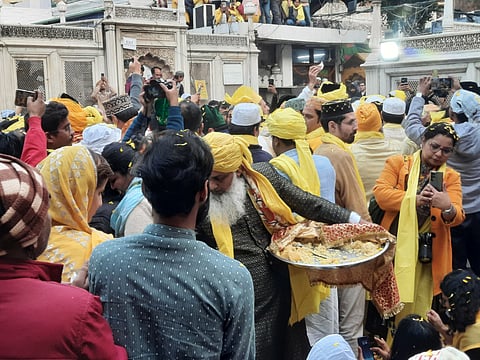A person distributes sweets after the sheet (chadar) hanging and qawwali session