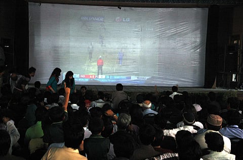 People watch a cricket match together
