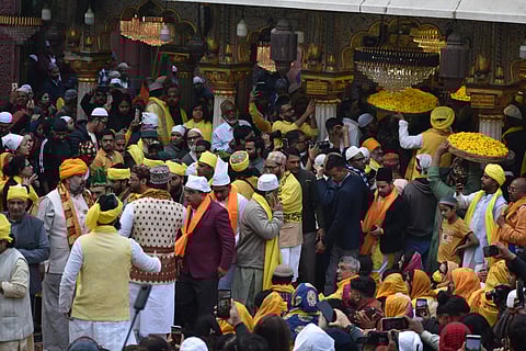 A group of dignitaries, caretakers and direct descendents of the Sufi, walk around the tomb as people sit around