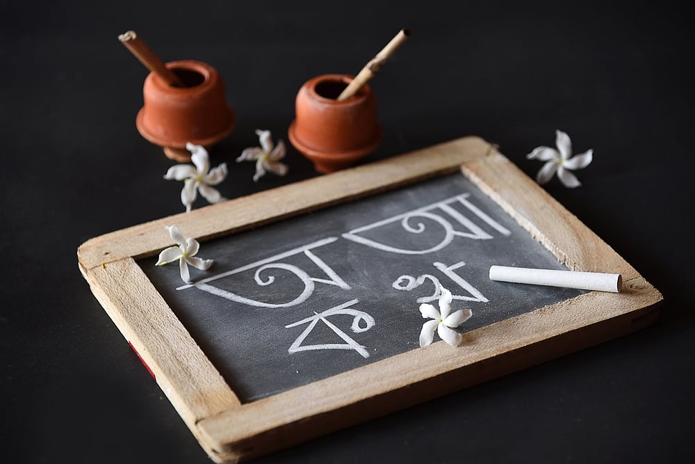 Earthen ink pot, quill and Bengali alphabets written on a slate during Saraswati Pujo