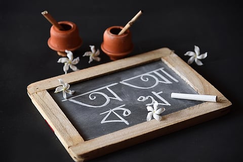 Earthen ink pot, quill and Bengali alphabets written on a slate during Saraswati Pujo