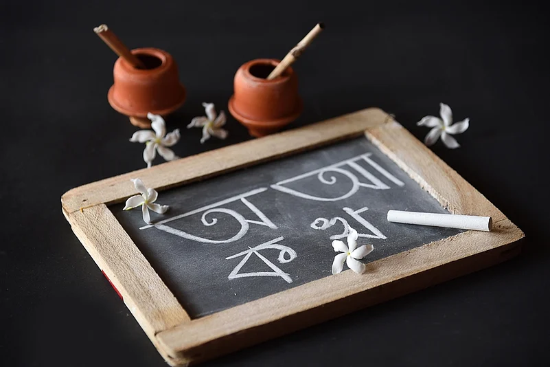 Earthen ink pot, quill and Bengali alphabets written on a slate during Saraswati Pujo