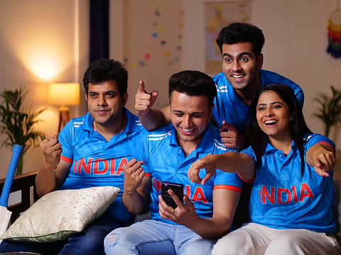 A group of friends watch a cricket match