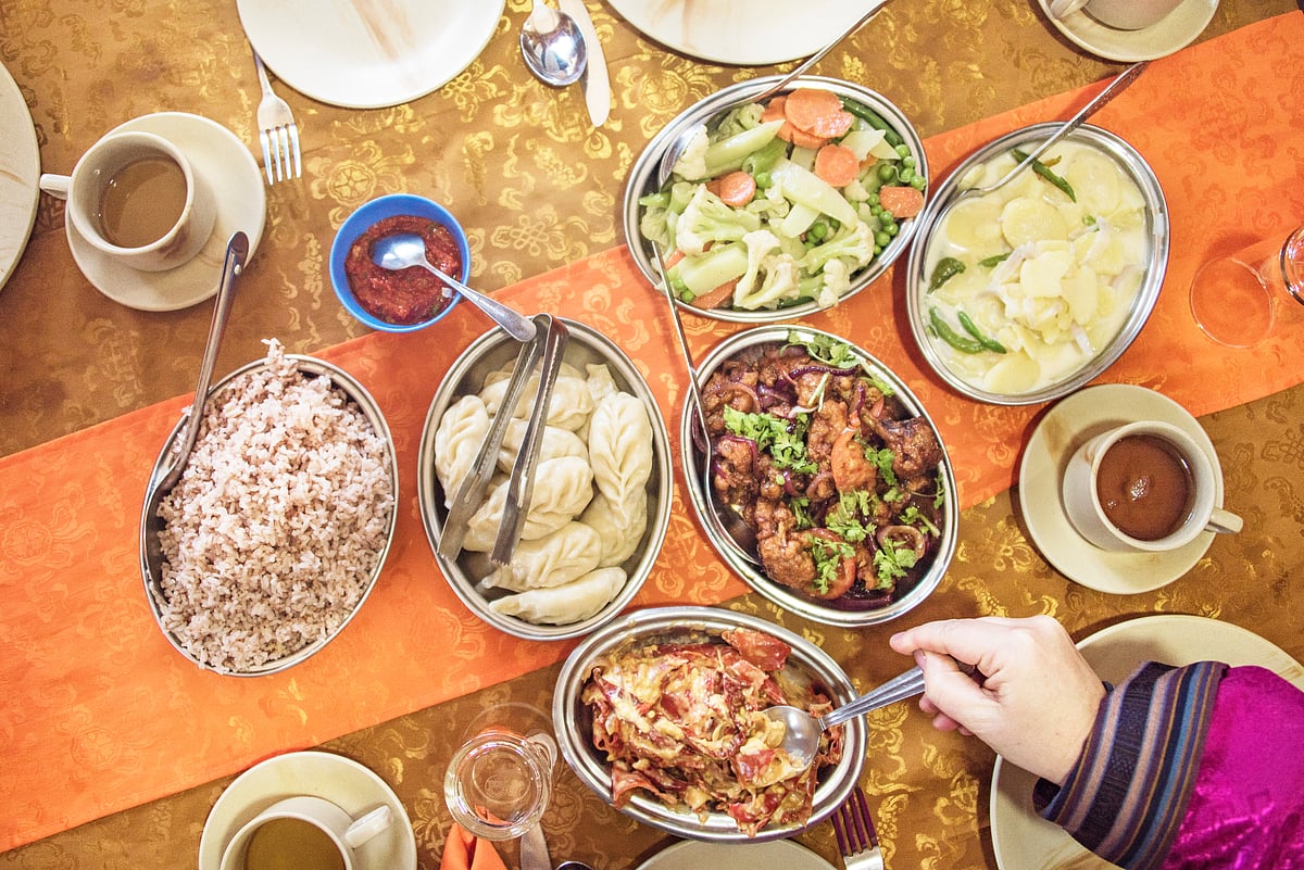 Bhutanese meal with chili cheese red rice, cheesy potato, chicken and vegetables