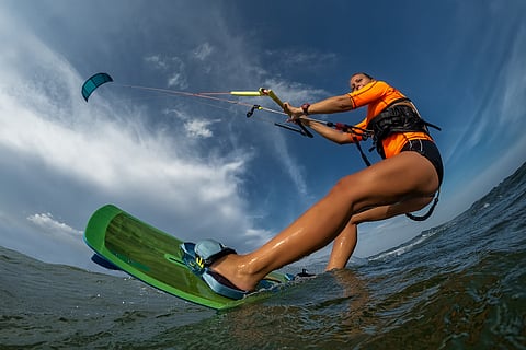 Kitesurfing or kiteboarding harnesses the wind and a power kite to pull riders along the water