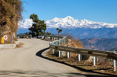Shutterstock : A road in Mussoorie with the view of Himalayan peaks at the far end