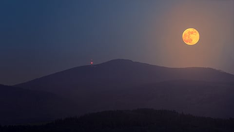 The rising Flower Moon over the Sudetes mountains in the Czech Republic