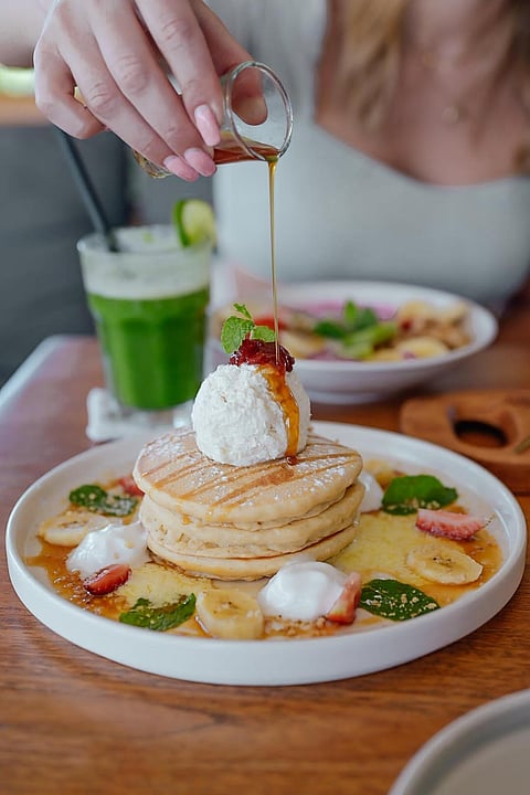 Drizzling maple syrup onto pancakes