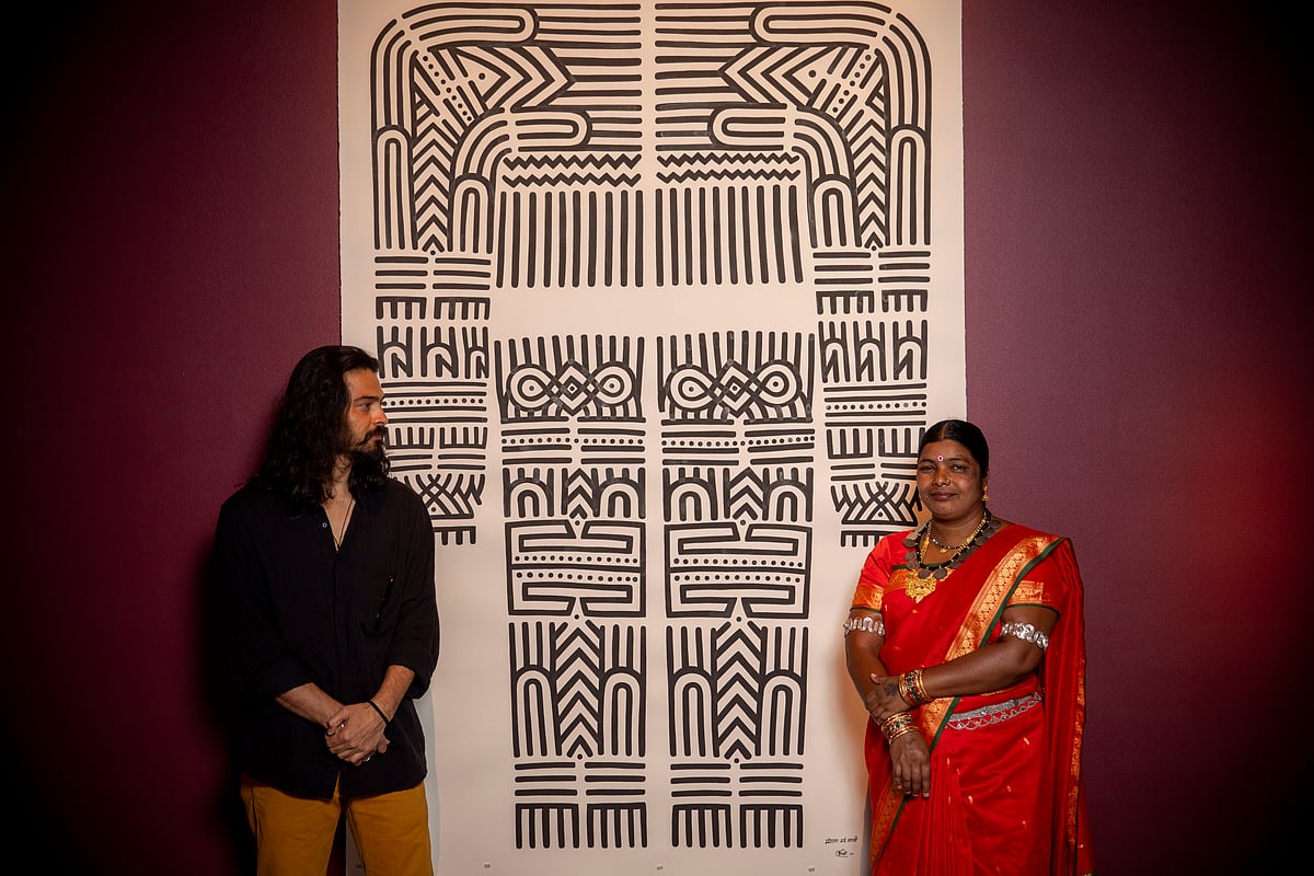 Amit Arjel-Sharma and Mangala Bai Maravi stand in front of their paintings 