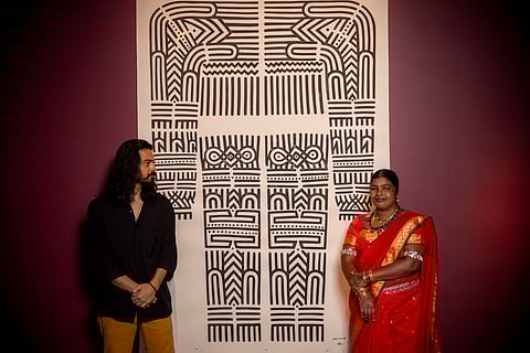 Amit Arjel-Sharma and Mangala Bai Maravi stand in front of their paintings