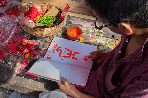 A priest draws auspicious religious signs on the front pages of new accounts books for starting the new year in Bengal 