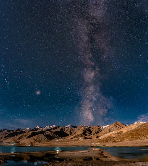 Panorama of arching Milky Way galactic center over the mountain at Pangong Lake