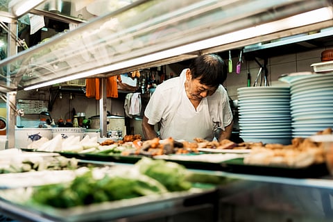 A man in apron preparing traditional Chinese food at a street food stall in Singapore