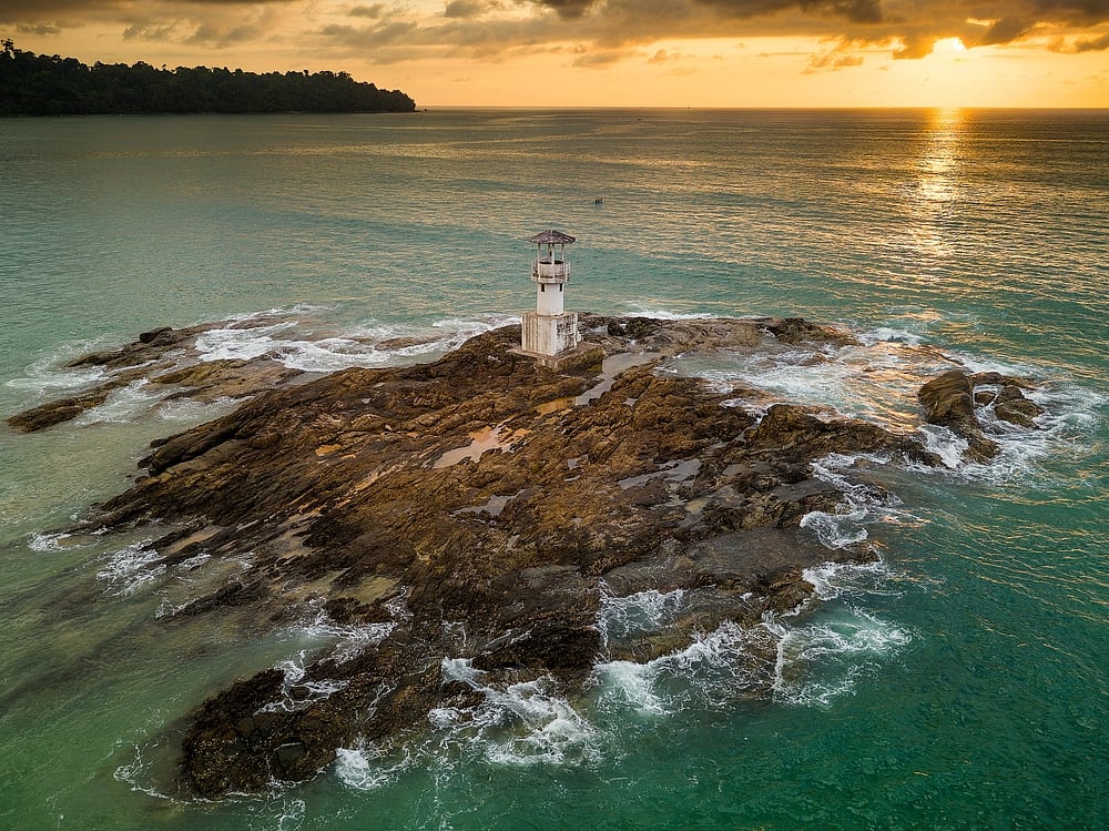 Aerial view of a tropical sunset with a lighthouse in the foreground in Khao Lak