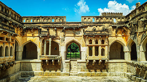 Queen's Bath in Hampi showcases the ruins of an ornate, historic bathing chamber used by the king and his wives, with an outdoor pool