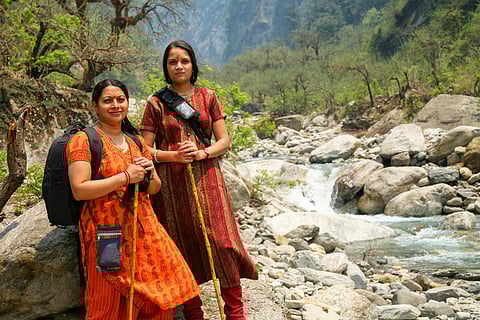 Hikers carrying walking poles and a backpack during their Kedarnath trek in the summer