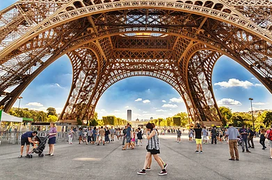 Feel good studio/Shutterstock : Tourists walking under Eiffel Tower