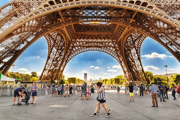 Feel good studio/Shutterstock : Tourists walking under Eiffel Tower