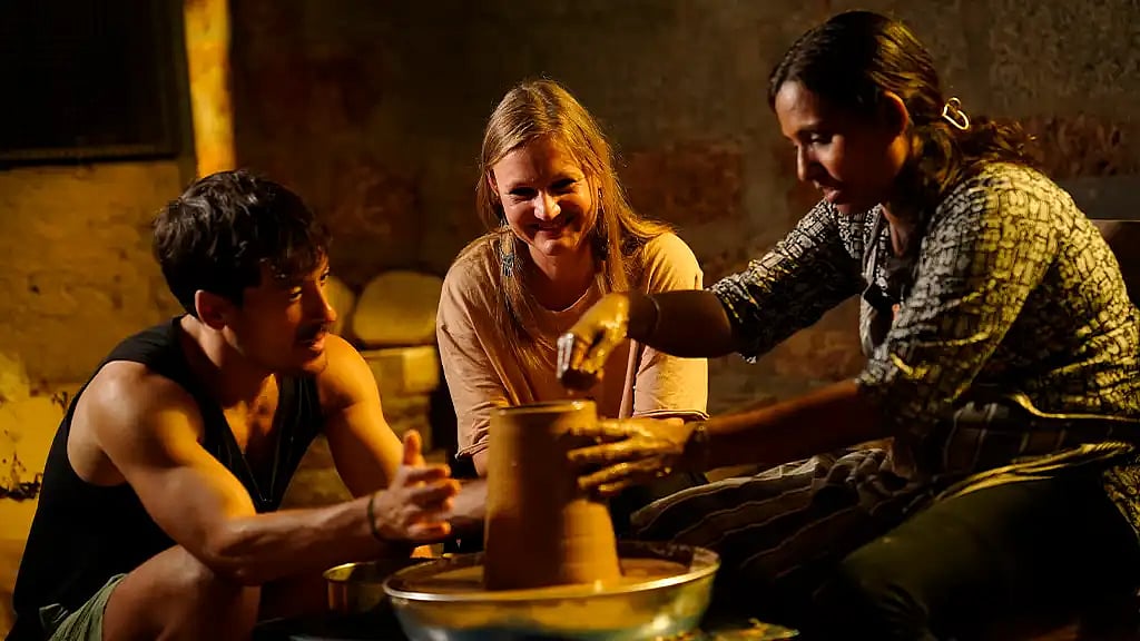 P. B. Bidula Baijunath (right), a renowned terracotta artist from Kozhikode, shows visitors how to make pottery in her clay studio