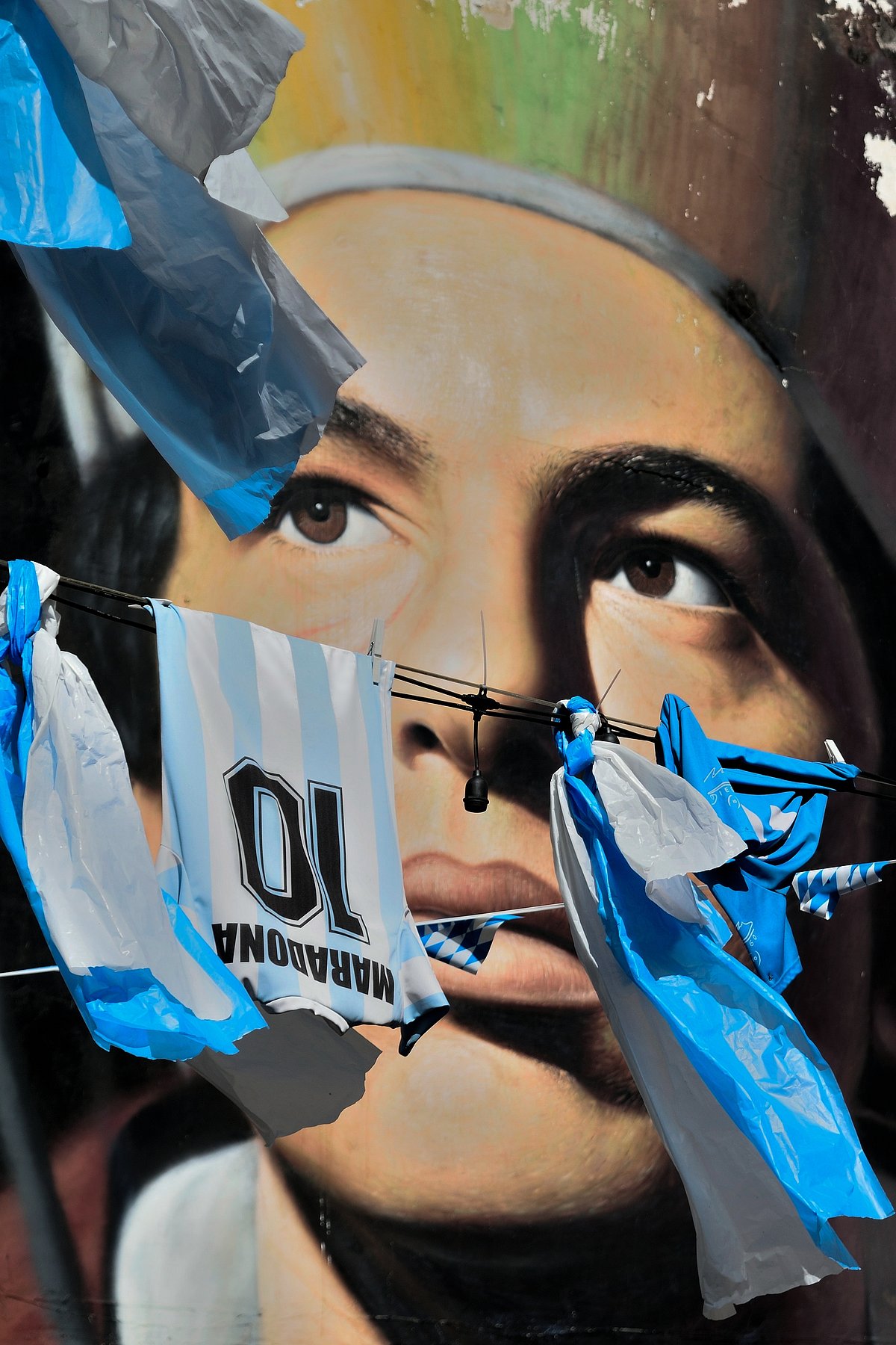 Shutterstock : The famous portrait of San Gennaro by the street artist Jorit and a Maradona t-shirt in the same photo between the sacred and the profane