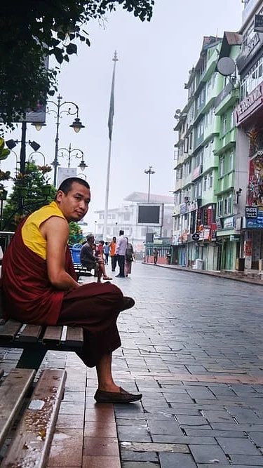 Shutterstock : A monk sits on a bench in Mahatma Gandhi Marg
