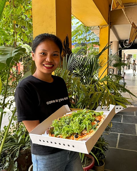 A Greenr Café staff member carrying a plant-based pizza