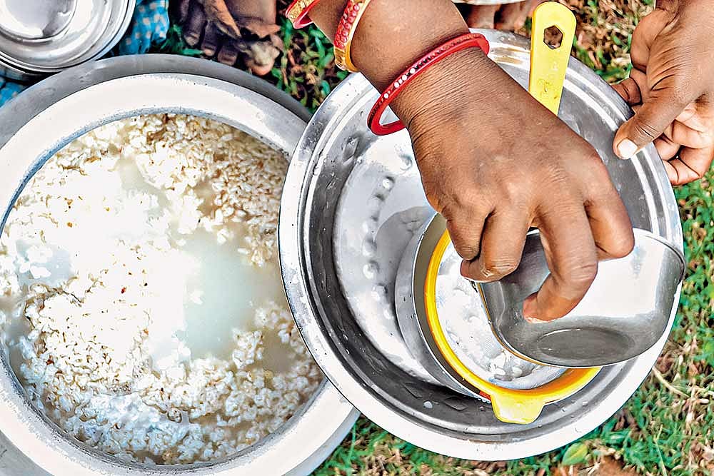 A tribal woman pours Handia for a customer
