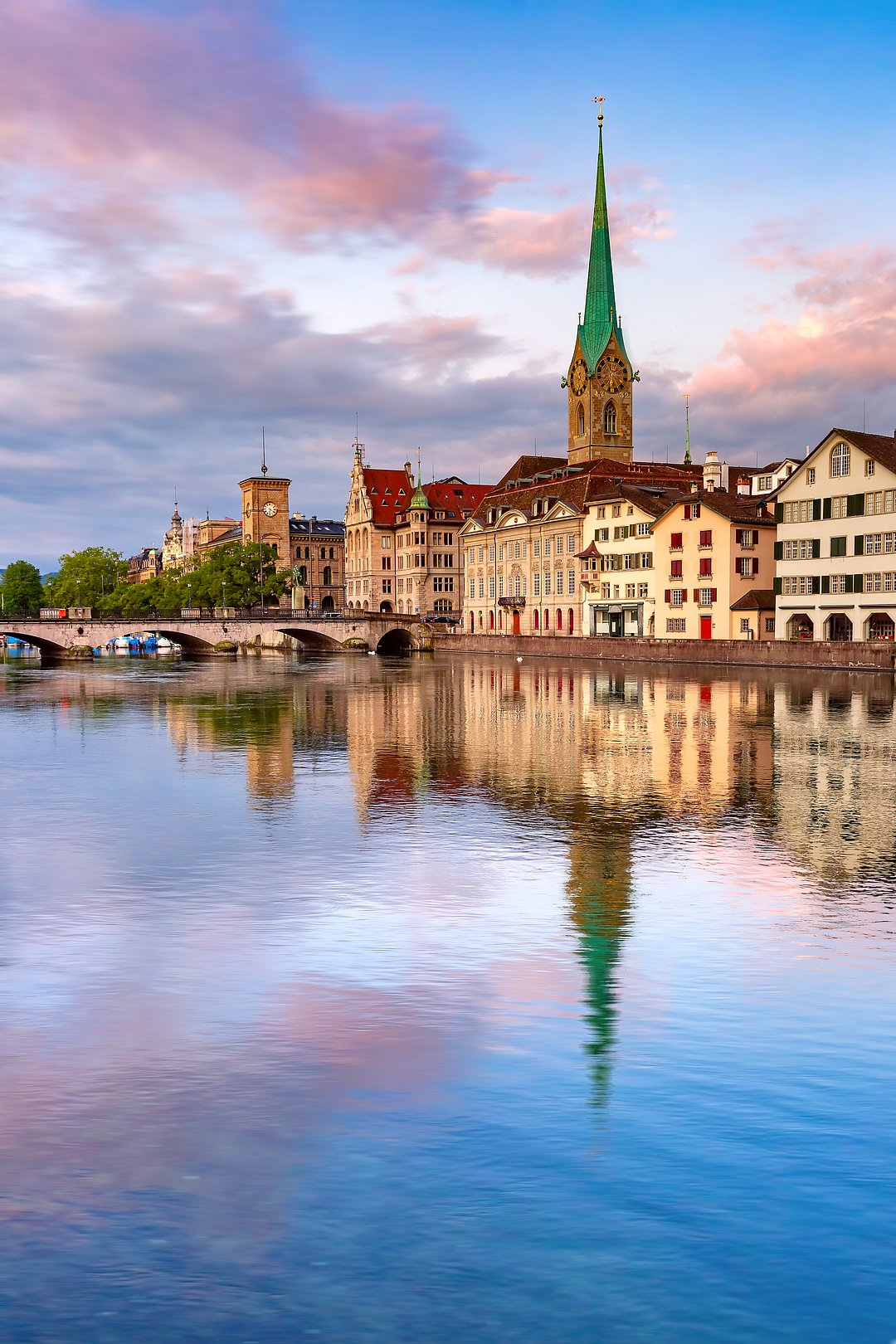 Famous Fraumunster church with reflections in river Limmat at pink sunrise in Old Town of Zurich