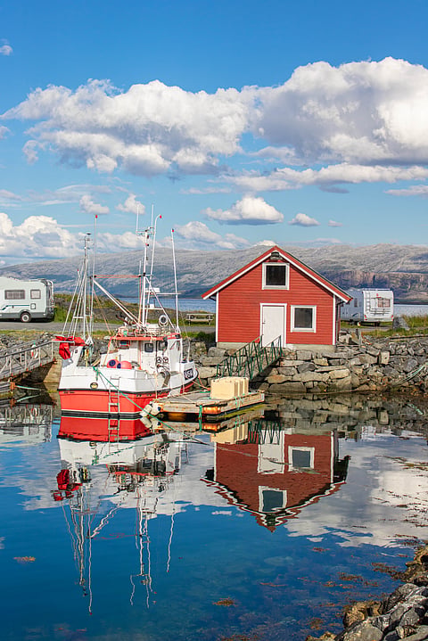 Nature and traditional houses and boats in the coastline of Vega Archipelago, stairs up the mountain, Helgeland Coast