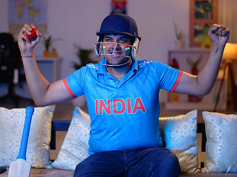 Excited young Indian man wearing cricket jersey and helmet