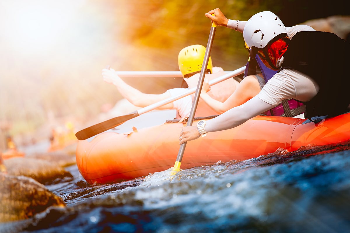 Close-up of young people rafting on the river turbulent flow with sunbeam
