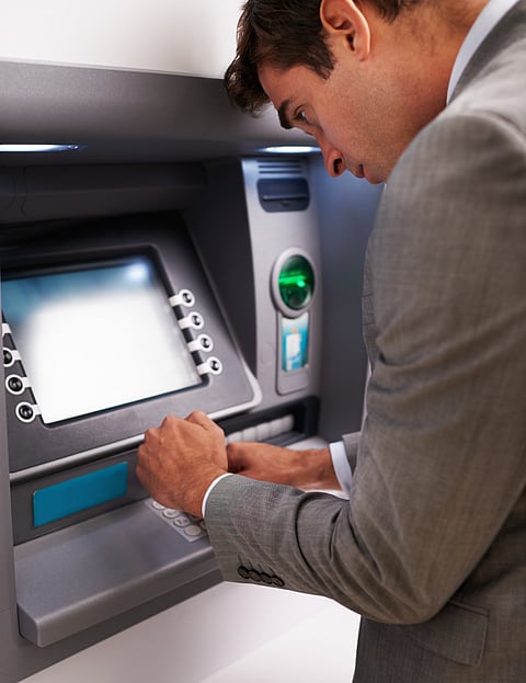 A man observing much needed secrecy at an ATM