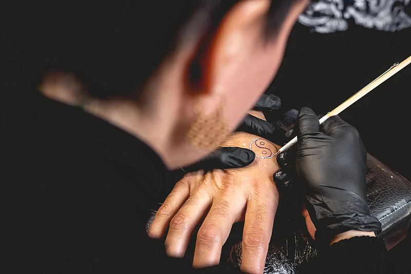 A young tattoo artist practices hand poke tattoo