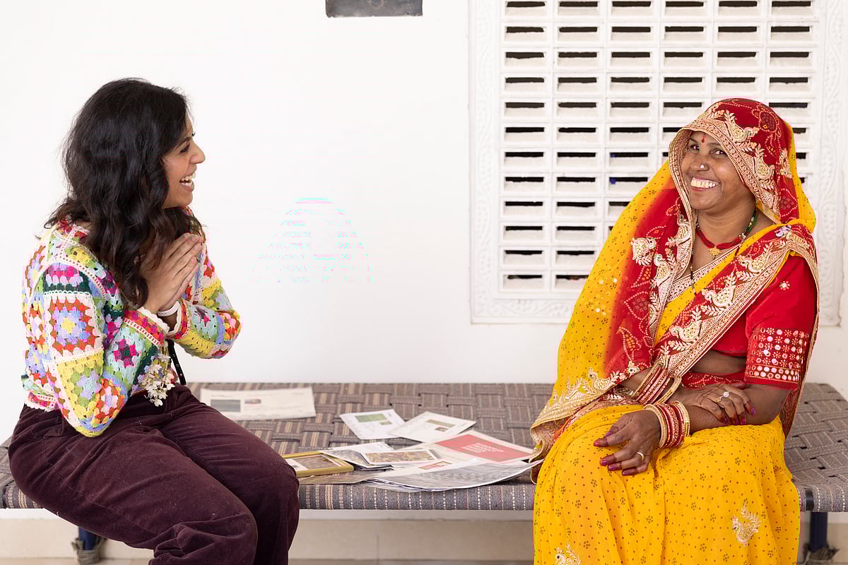 A visitor interacts with an artisan from Jaipur Rugs
