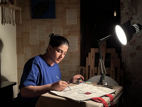 Maryam paints on a tote bag