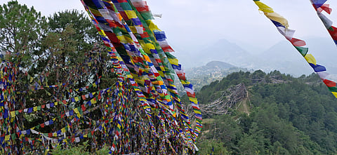 Colourful prayer flags fluttering in the wind mark the trail to the sacred stupa