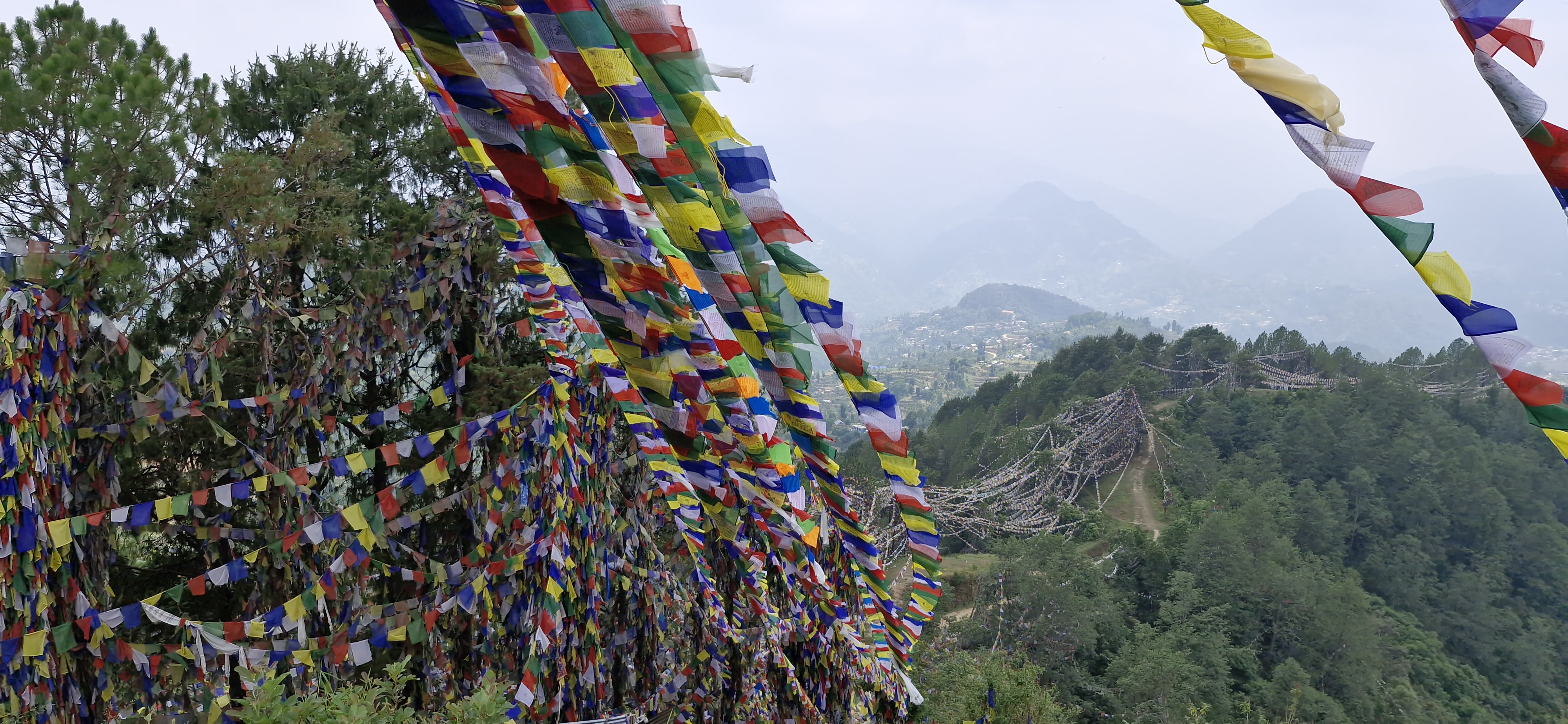 Colourful prayer flags fluttering in the wind mark the trail to the sacred stupa
