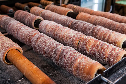 Trdelník is a kind of spit cake made from dough wrapped around a stick, baked, and topped with sugar and walnut mix. It is eaten in the Czech Republic and Hungary