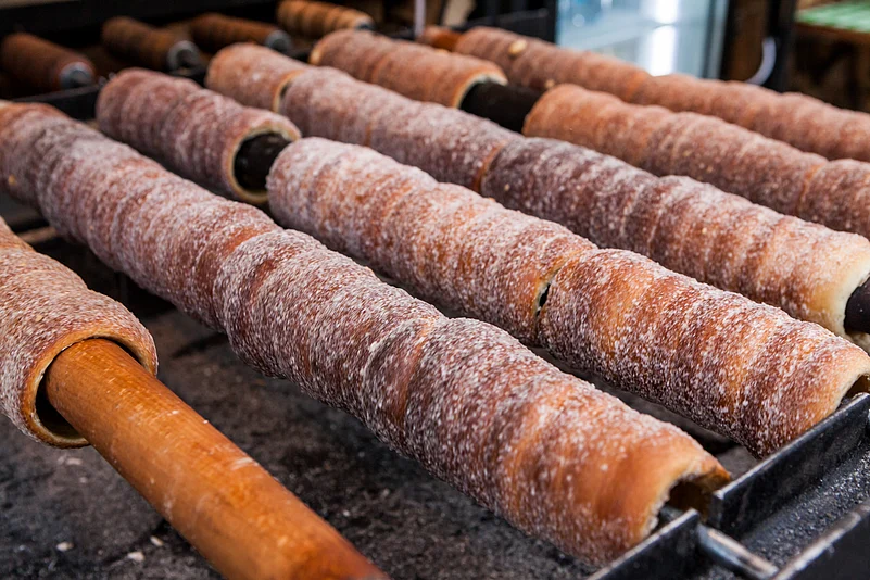 Trdelník is a kind of spit cake made from dough wrapped around a stick, baked, and topped with sugar and walnut mix. It is eaten in the Czech Republic and Hungary