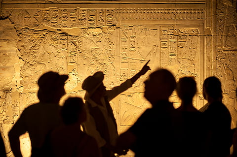 A tour guide at his job telling the tourists about ancient Egyptian hieroglyphs