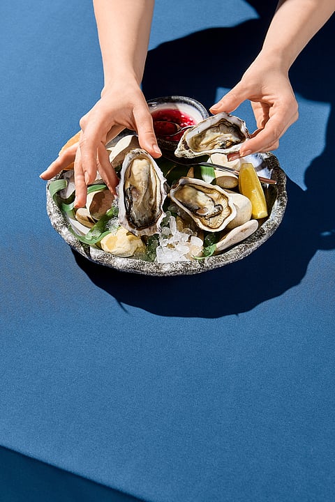 A view of a woman's hand picking up a fresh oyster
