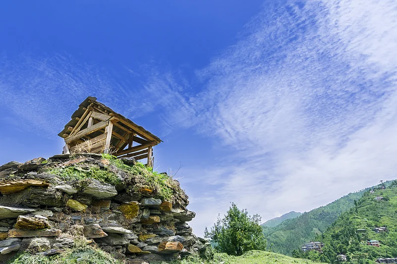 A small wooden hut on top of a mountain surrounded by nature in the Janjehli Valley