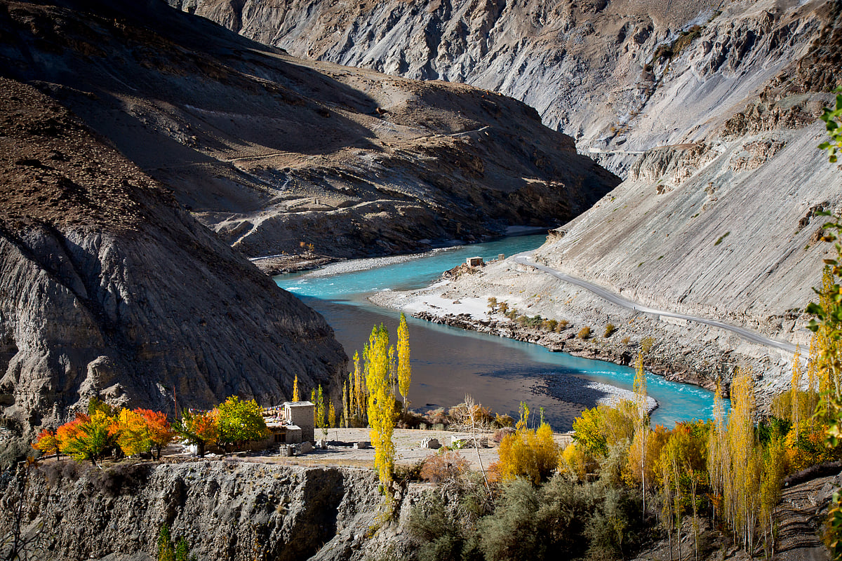 A traditional Tibetan house among colourful apricot trees against the Zanskar River in Chilling village