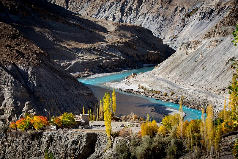 A traditional Tibetan house among colourful apricot trees against the Zanskar River in Chilling village