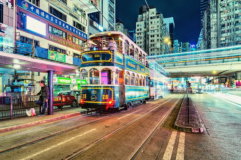 A retro tram glides through the evening city street, Hong Kong
