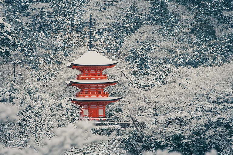 A red Japanese pagoda is blanketed in white snow in Kyōto City - Shutterstock