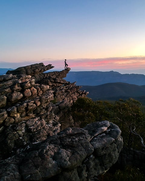 Hiker standing on cliff edge at sunset in the Grampians National Park