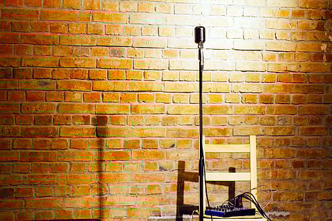 Microphone ready on stage against a brick wall